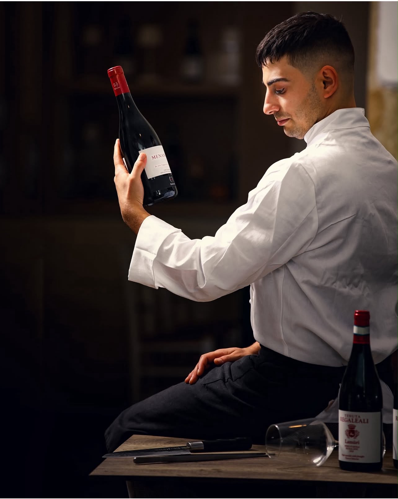 Lo chef Sergio Amodeo osserva una bottiglia di vino